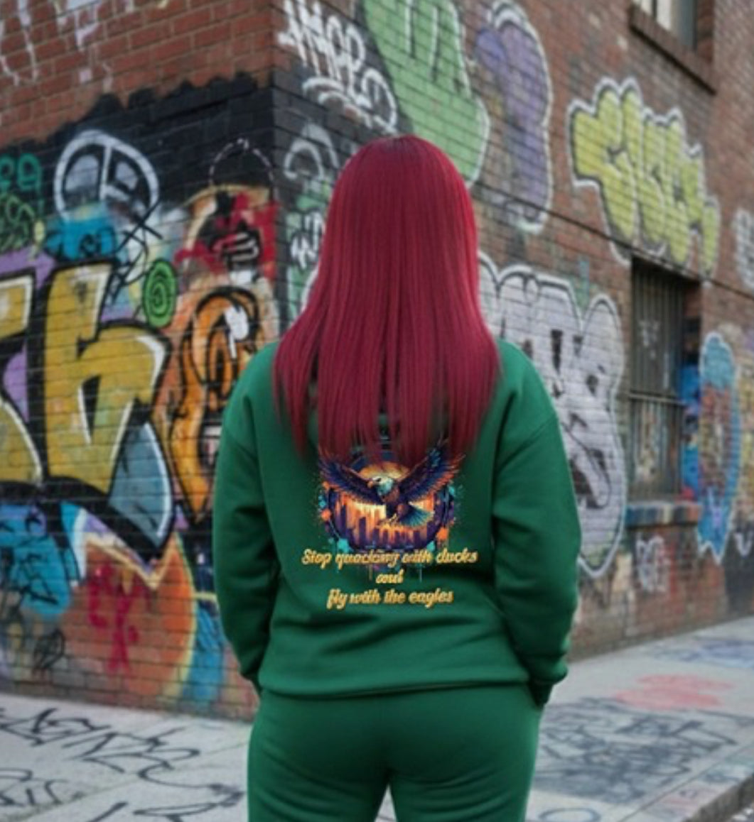 Fly With The Eagles- HOODIE worn by a person with long red hair against a graffiti backdrop, showcasing streetwear style.