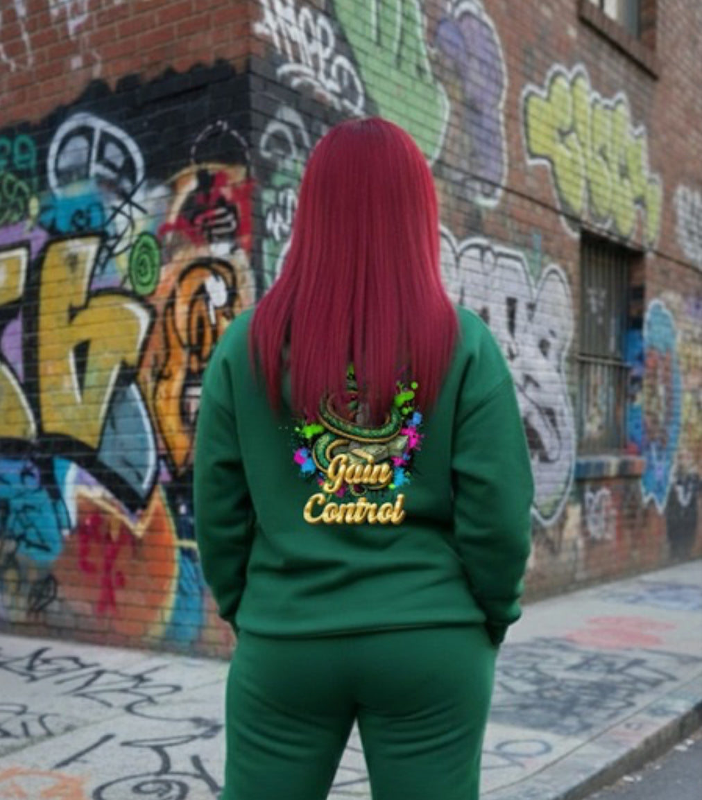 Back view of woman in green hoodie with 'Gain Control' design, standing against colorful graffiti wall in streetwear style.