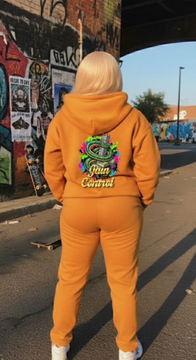 A model wearing the Gain Control- HOODIE, a stylish pullover in orange with a vibrant back design, perfect for streetwear.