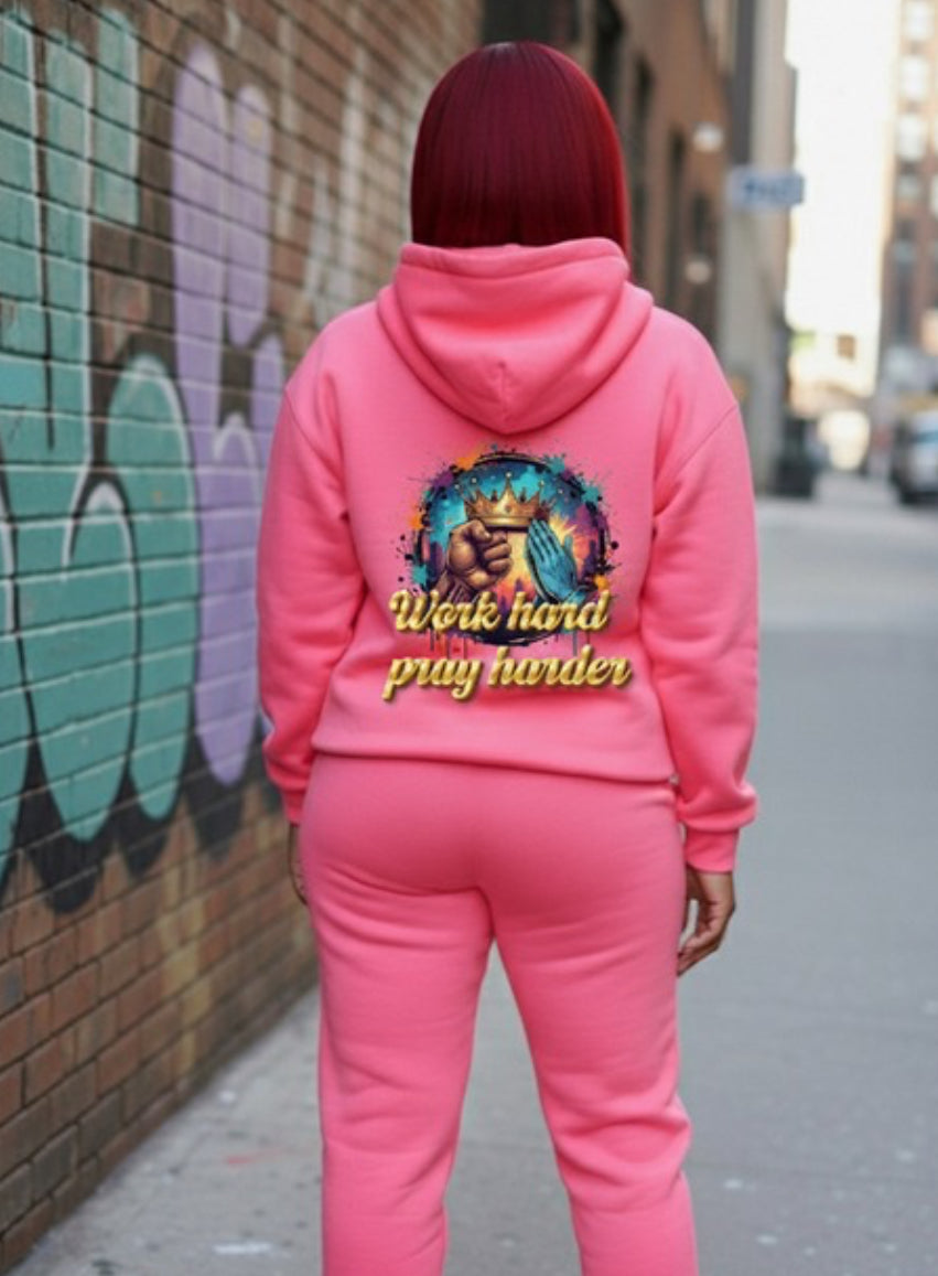 Work Hard- HOODIE in pink worn by a model showcasing the back design on a street background.