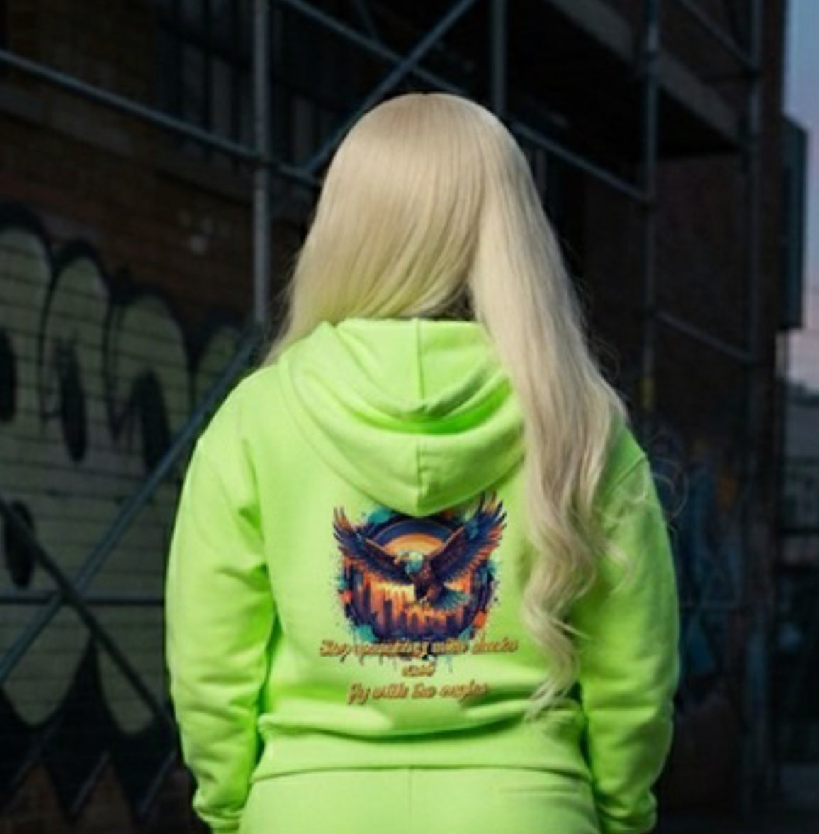 Back view of a model wearing a neon hoodie featuring an eagle design and the text 'Fly With The Eagles- HOODIE'.