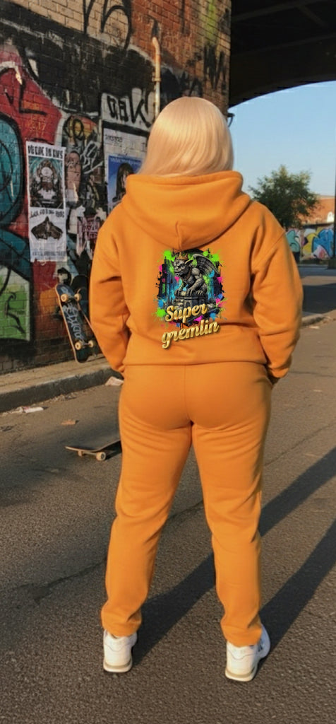 Model wearing Super Gremlin- HOODIE in vibrant orange, showcasing streetwear style with colorful graphic design.