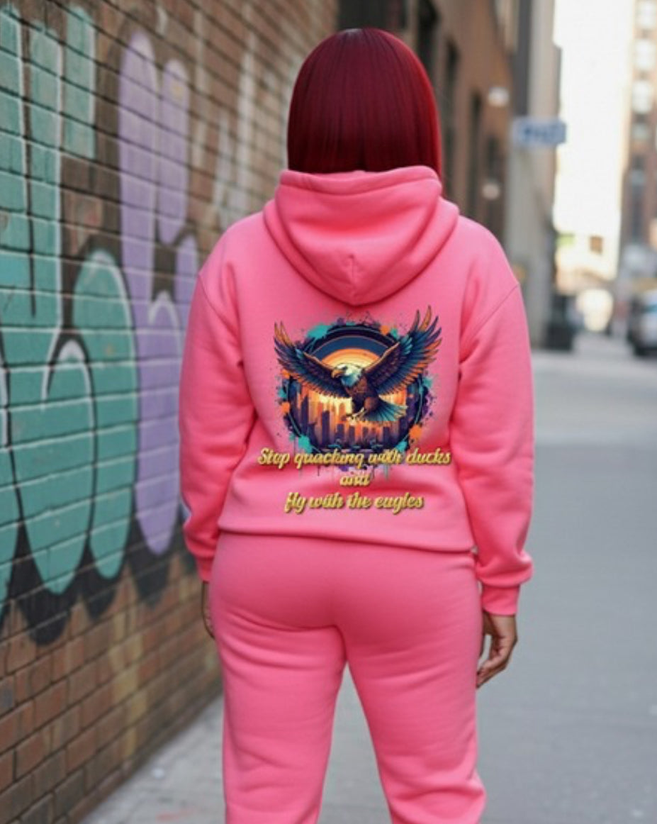 A model wearing the Fly With The Eagles- HOODIE in pink, showcasing its vibrant design and streetwear style.